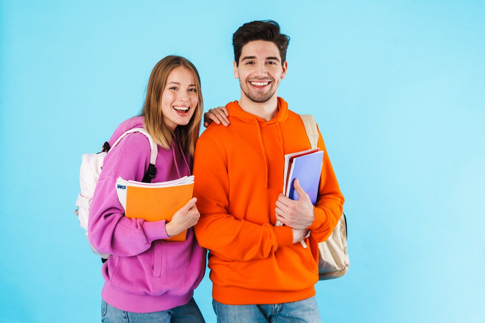Portrait,Of,A,Cheerful,Young,Couple,Of,Students,Wearing,Backpacks,
